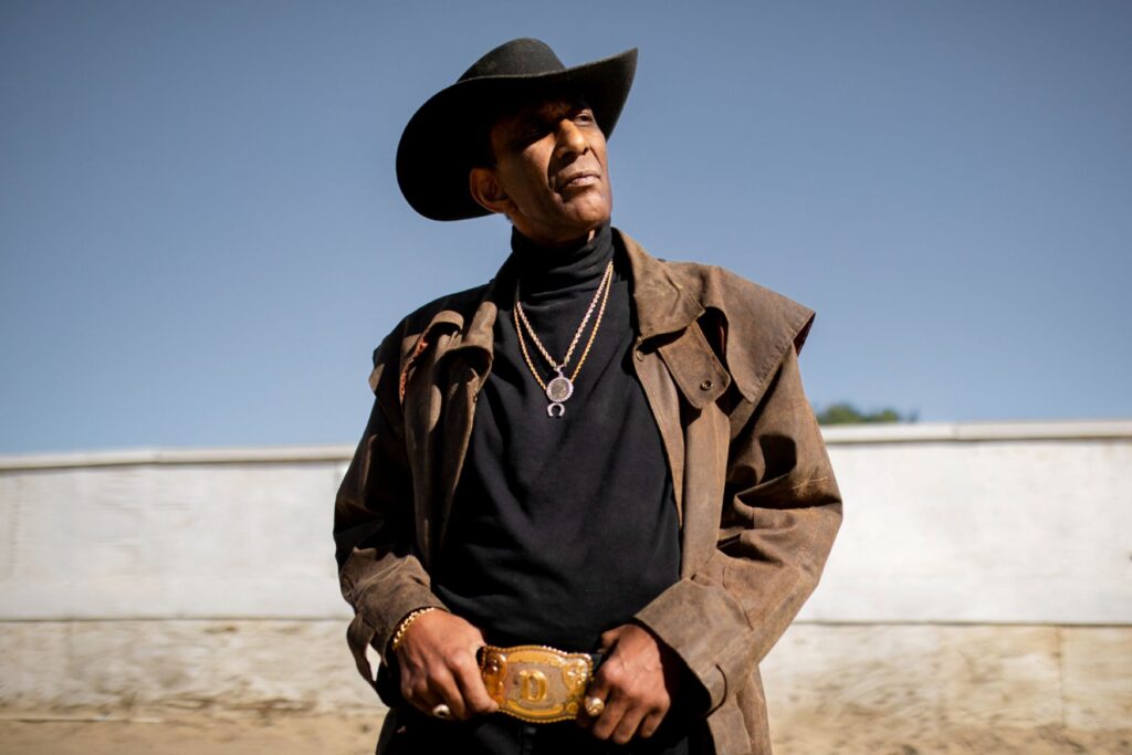 A Black cowboy standing under the sun.